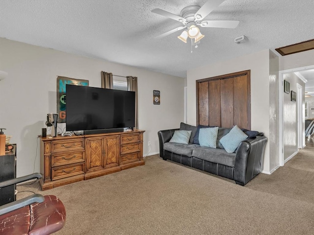 living area featuring a textured ceiling, carpet floors, a ceiling fan, and baseboards