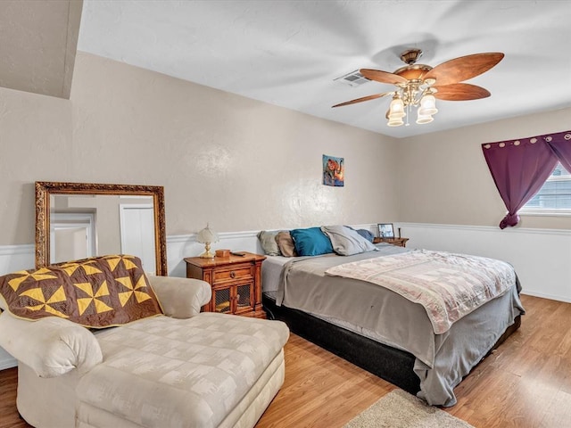 bedroom with ceiling fan, wood finished floors, and visible vents