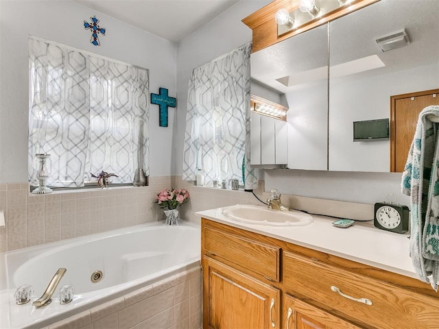 bathroom featuring a tub with jets, visible vents, a wealth of natural light, and vanity