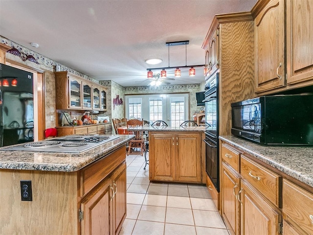 kitchen featuring glass insert cabinets, light tile patterned flooring, a peninsula, black appliances, and wallpapered walls