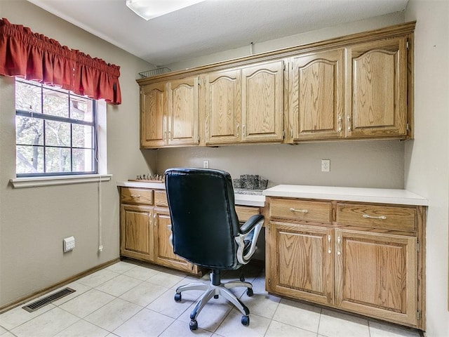 home office featuring built in study area, visible vents, baseboards, and light tile patterned floors