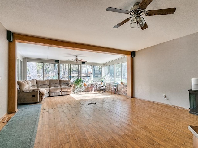 unfurnished living room featuring a textured ceiling, light wood finished floors, beamed ceiling, and a healthy amount of sunlight