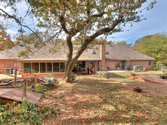 rear view of house featuring a sunroom, central AC unit, and brick siding