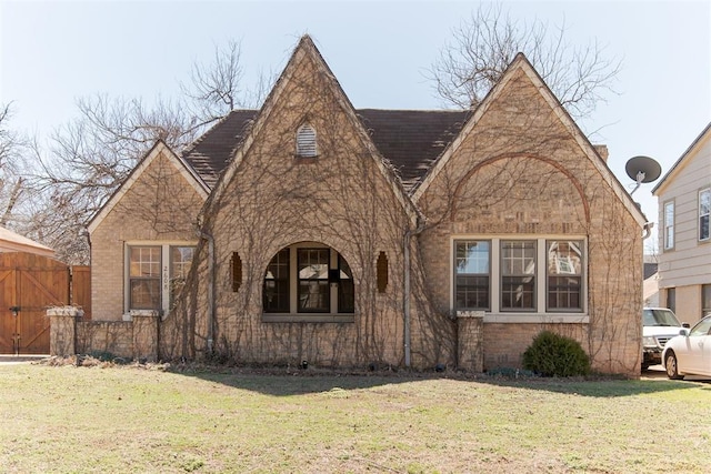 tudor-style house featuring a front lawn and brick siding