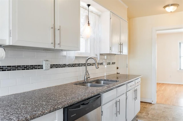 kitchen featuring tasteful backsplash, dishwasher, dark stone countertops, white cabinetry, and a sink