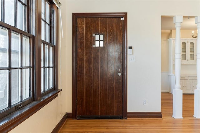 interior space with light wood-type flooring, baseboards, and ornate columns