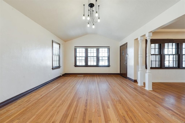 spare room featuring lofted ceiling, light wood finished floors, decorative columns, and baseboards