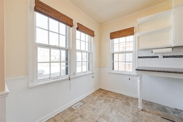 unfurnished dining area featuring a wainscoted wall, visible vents, and crown molding