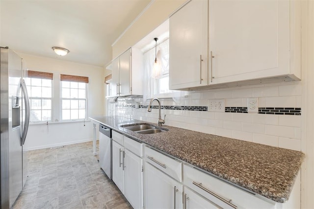 kitchen featuring stainless steel appliances, white cabinetry, a sink, and decorative backsplash