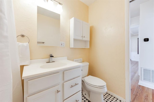 bathroom featuring toilet, baseboards, visible vents, and vanity