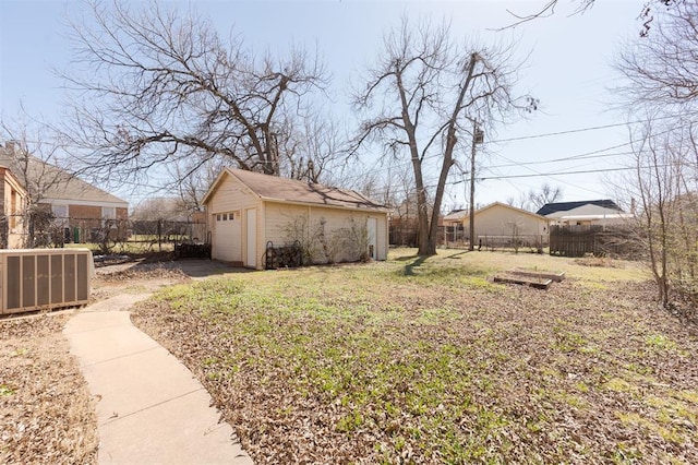 view of yard featuring an outbuilding, a detached garage, cooling unit, and fence