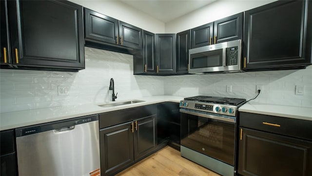 kitchen with light countertops, appliances with stainless steel finishes, a sink, and decorative backsplash