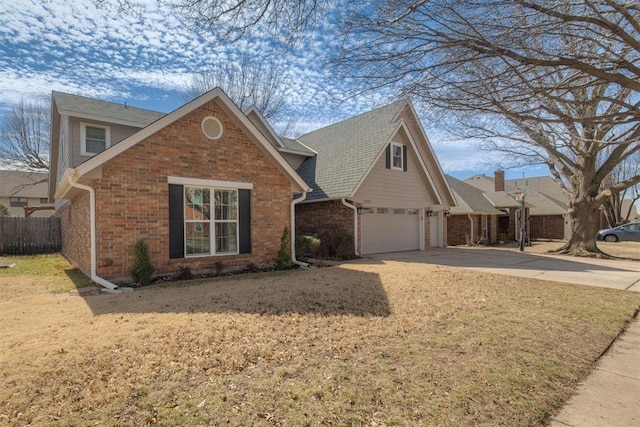 traditional home featuring a garage, brick siding, driveway, and fence