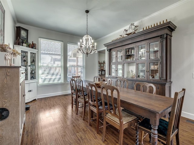 dining space featuring baseboards, ornamental molding, dark wood finished floors, and a notable chandelier