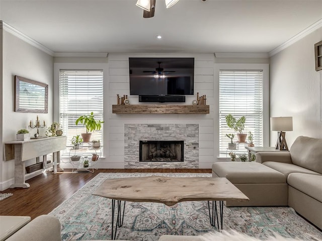 living area featuring ornamental molding, wood finished floors, a ceiling fan, and a stone fireplace