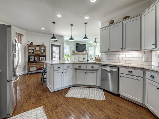 kitchen with decorative backsplash, appliances with stainless steel finishes, dark wood-type flooring, a sink, and a peninsula