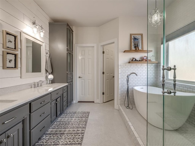 bathroom featuring tile patterned flooring, a sink, tile walls, a soaking tub, and double vanity