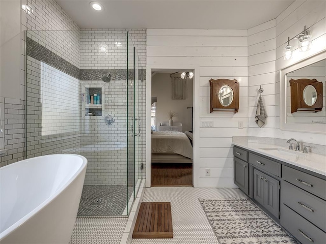 bathroom with ensuite bathroom, a shower stall, vanity, tile patterned flooring, and a freestanding tub