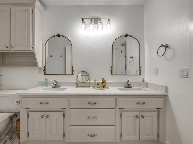 bathroom featuring toilet, double vanity, and a sink