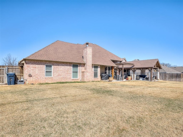 rear view of property featuring a lawn, a chimney, a gazebo, and fence