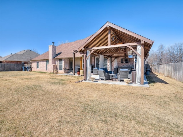 back of house with a patio, a fenced backyard, brick siding, an outdoor living space, and a yard