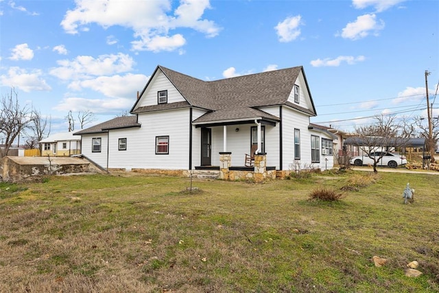 rear view of property featuring roof with shingles and a lawn