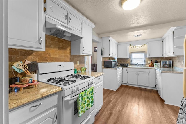 kitchen with light countertops, light wood-style floors, black microwave, white range with gas stovetop, and under cabinet range hood