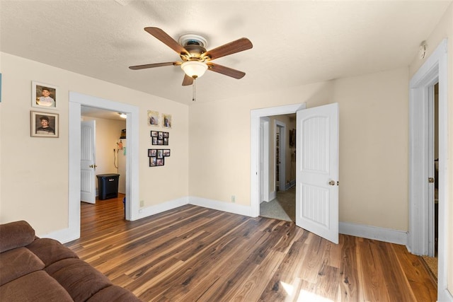 unfurnished living room featuring a ceiling fan, dark wood finished floors, and baseboards