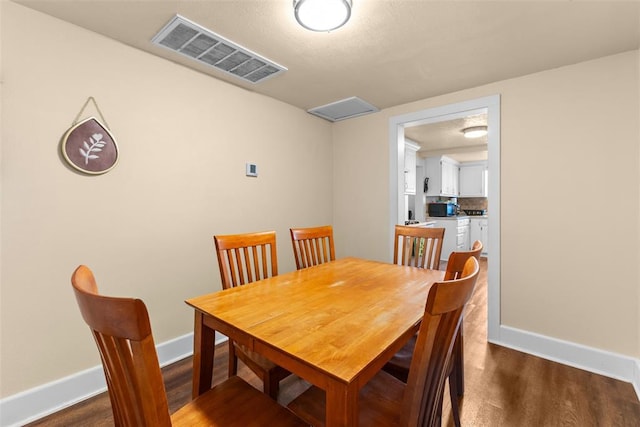 dining space featuring wood finished floors, visible vents, and baseboards