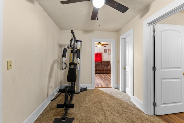 workout room featuring carpet, baseboards, and a textured ceiling