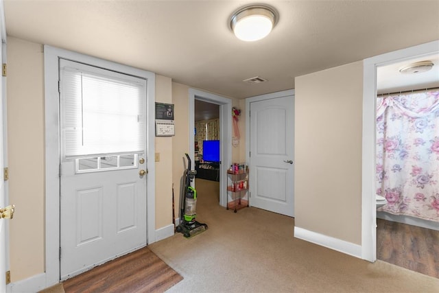 foyer entrance featuring carpet flooring, visible vents, and baseboards