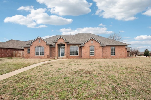 single story home with brick siding, roof with shingles, and a front yard