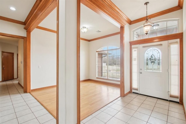 foyer featuring ornamental molding, light tile patterned flooring, a notable chandelier, and baseboards