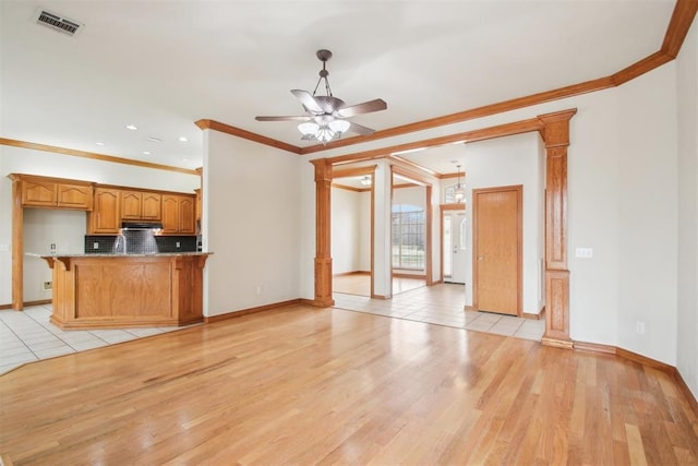 unfurnished living room with a ceiling fan, visible vents, ornamental molding, light wood finished floors, and ornate columns