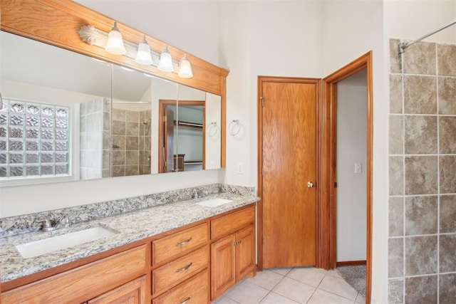 full bathroom featuring double vanity, a tile shower, a sink, and tile patterned floors