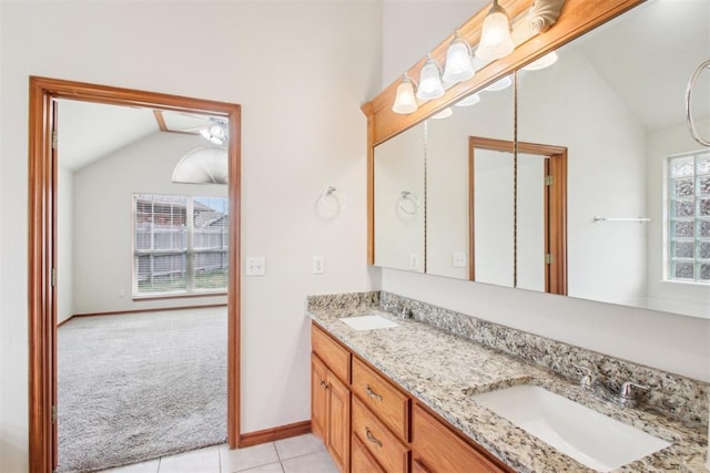 full bath featuring tile patterned flooring, vaulted ceiling, a sink, and double vanity