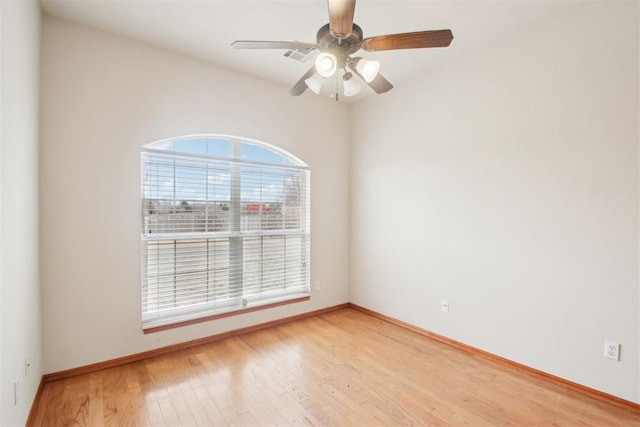 empty room with wood finished floors, a ceiling fan, and baseboards