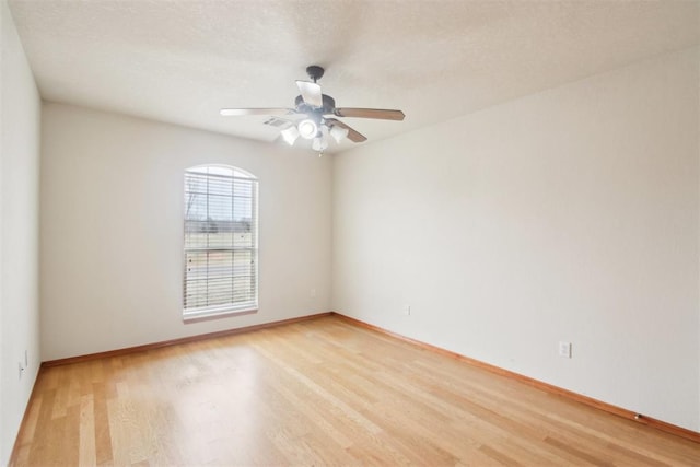 empty room with a ceiling fan, light wood-style flooring, baseboards, and a textured ceiling