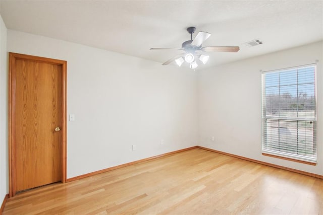 spare room with light wood-style floors, baseboards, visible vents, and ceiling fan