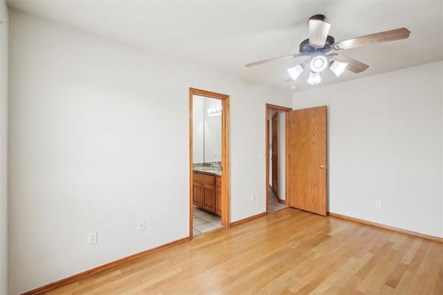 unfurnished bedroom featuring connected bathroom, light wood-style flooring, baseboards, and ceiling fan