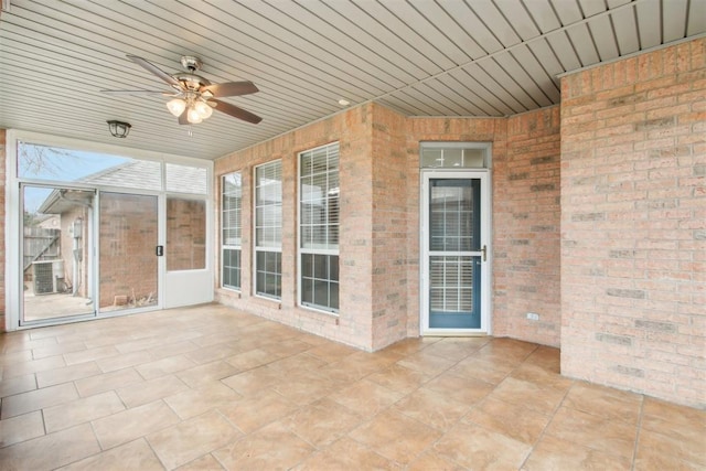 unfurnished sunroom with wood ceiling and a ceiling fan