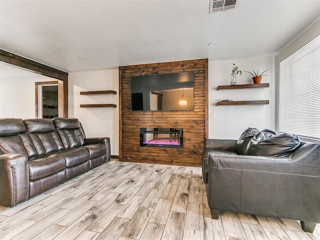 living area featuring a large fireplace, visible vents, and wood finished floors