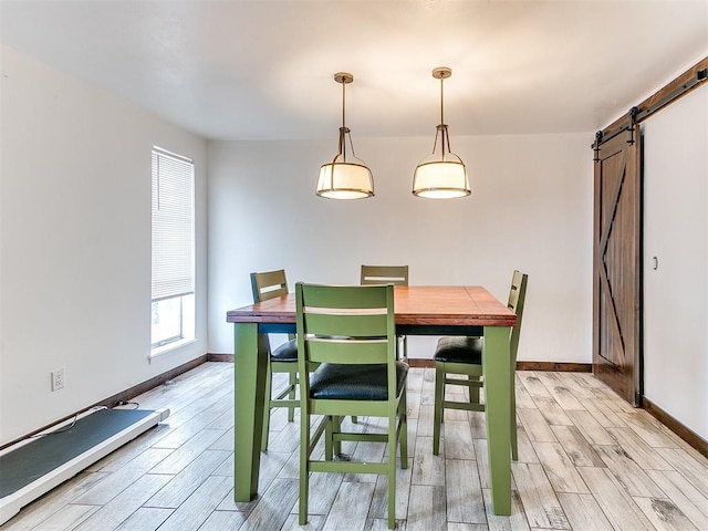 dining space featuring a barn door, wood finish floors, and baseboards