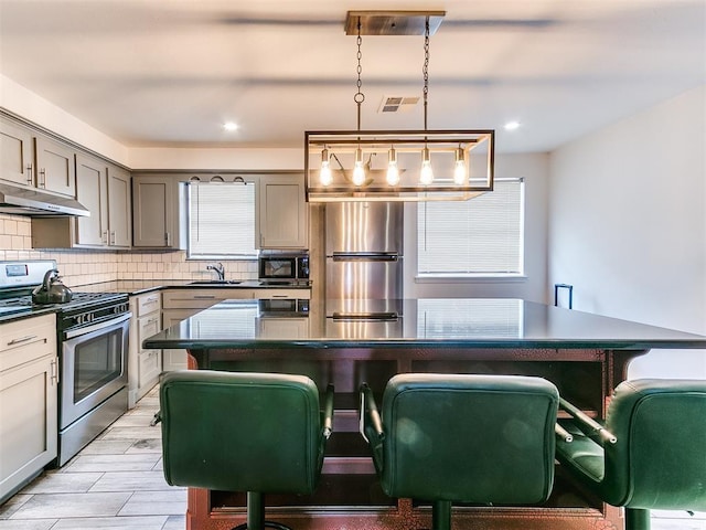 kitchen with dark countertops, visible vents, appliances with stainless steel finishes, and a sink