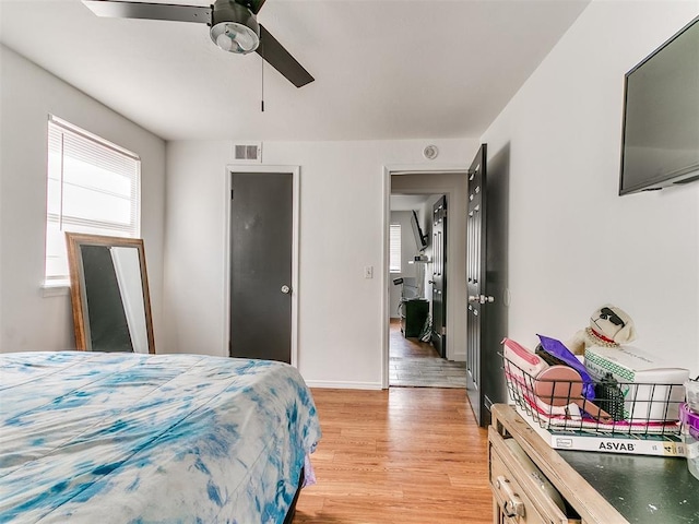 bedroom with a ceiling fan, visible vents, light wood-style flooring, and baseboards