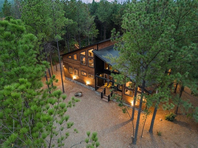 exterior space featuring gravel driveway, a wooded view, and metal roof