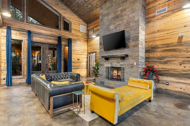 living room featuring concrete flooring, high vaulted ceiling, an outdoor stone fireplace, wood walls, and wood ceiling