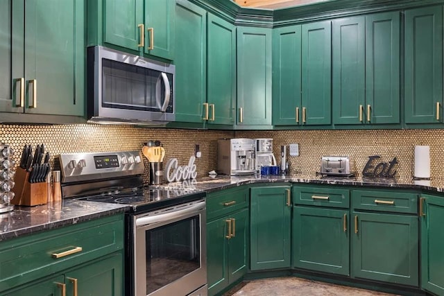 kitchen with backsplash, appliances with stainless steel finishes, green cabinets, and dark stone countertops