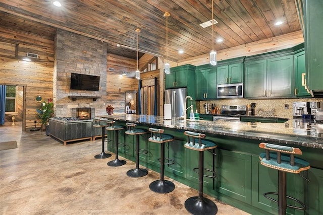 kitchen featuring wood walls, wooden ceiling, stainless steel appliances, and green cabinets