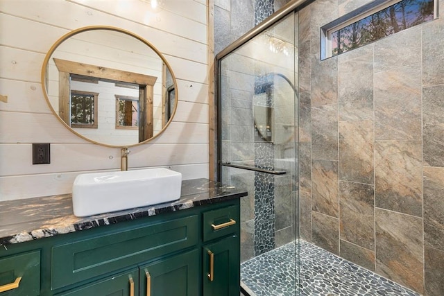 full bathroom featuring vanity, wood walls, and a shower stall